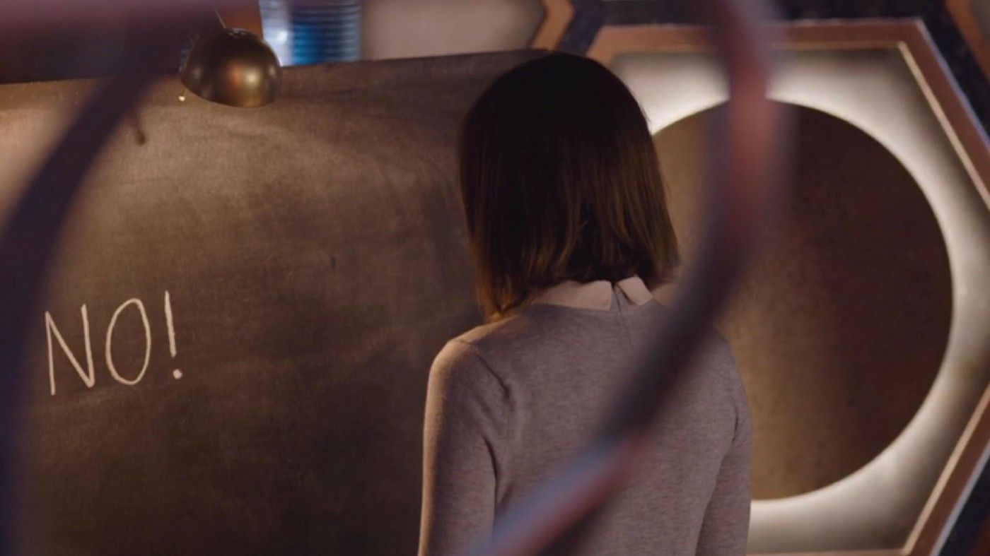 A screencap from 'Heaven Sent'. Clara in the TARDIS, her back turned to the Doctor, so she is facing a chalkboard which reads 'NO!'